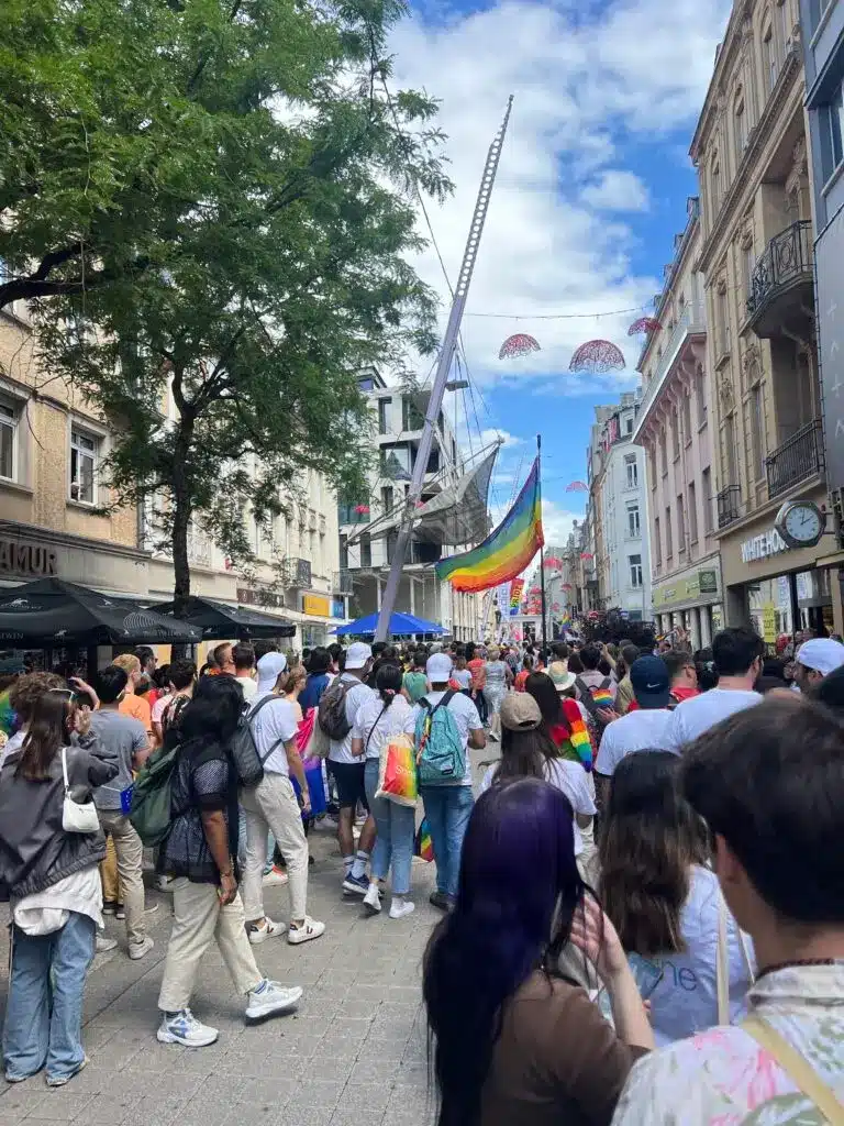 An LGBTQIA+ sign displayed in a city square; LuxCitizenship stats show more LGBTQIA+ members interested in EU citizenship by ancestry. 