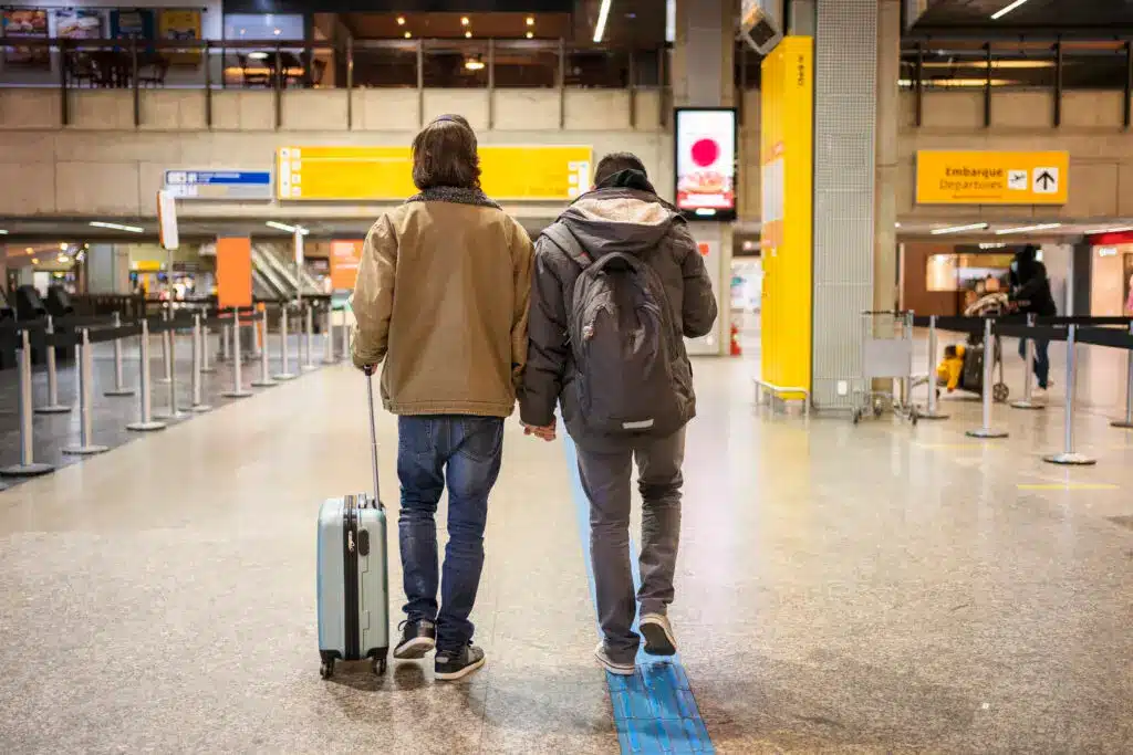 A couple travels through an airport, representing LGBTQIA+ growing interest in moving abroad and EU citizenship by ancestry. 